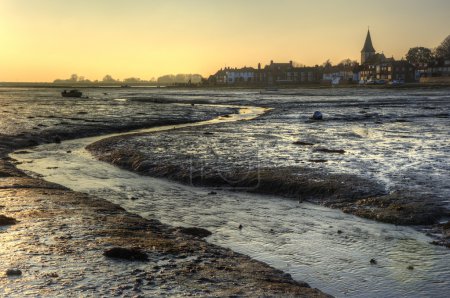 Low tide harbour at sunset with nearby town in distance nad stre