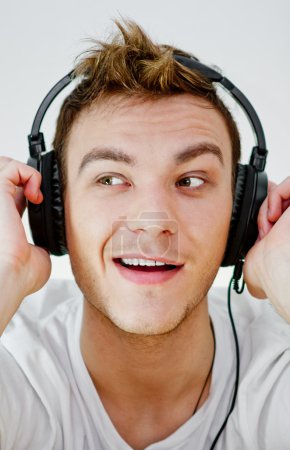 Young man wearing headphones and holding arms on them.