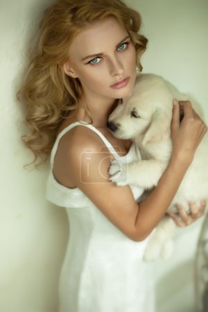 Young blonde beauty hugging a white puppy dog