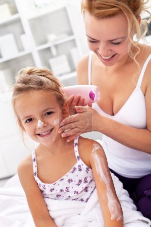 Body care - woman and little girl applying cream