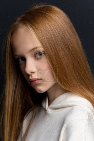 Close-up portrait of beautiful young redhead in studio on black background