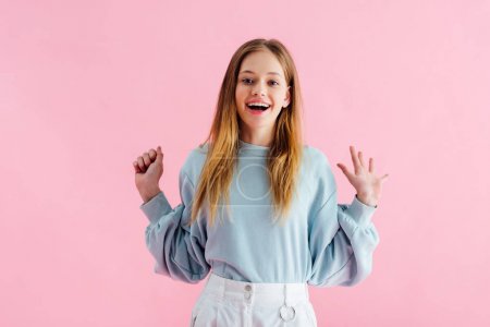 happy pretty teenage girl looking at camera isolated on pink