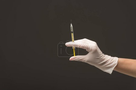 cropped view of doctor in latex glove holding syringe isolated on grey