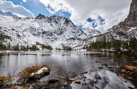 Lake Helene with rocks and mountains in snow, Rocky Mountain National Park in Colorado, USA. 