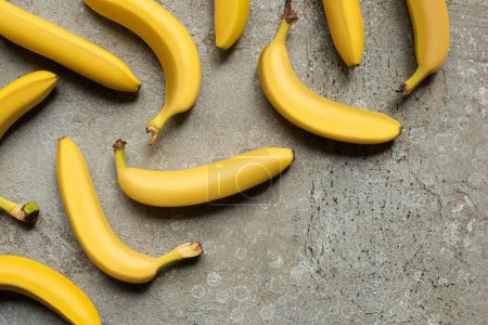 top view of colorful delicious bananas on grey concrete surface