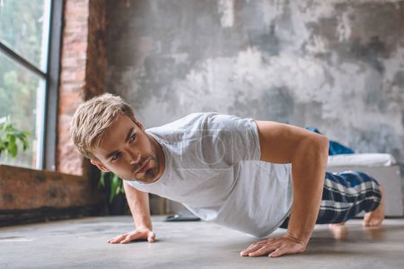 confident young man doing push ups during morning time at home 
