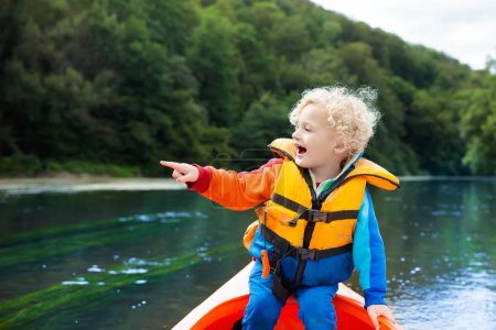 Child with paddle on kayak. Summer camp for kids. Kayaking and canoeing with family. Children on canoe. Little boy on kayak ride. Wild nature and water fun on summer vacation. Camping and fishing.