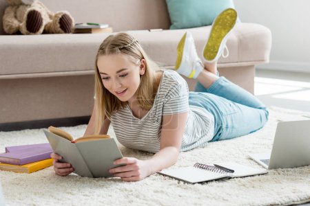 teen student girl reading book while lying on floor
