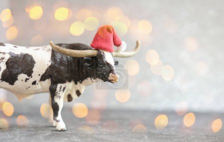 2021 year of the ox or bull. new year poster with toy bull in red hat defocused lights or bokeh. happy new year concept. selective focus.