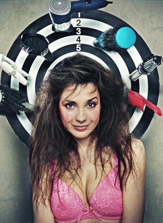 Cute brunette posing as a target with hairdresser's instruments