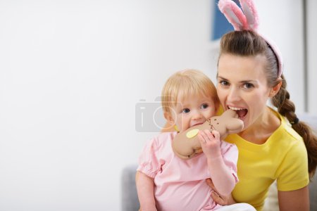 Mother and baby biting chocolate Easter rabbit cookie