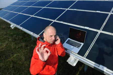 Engineer using laptop at solar panels plant field