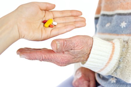 Giving pills to elderly woman
