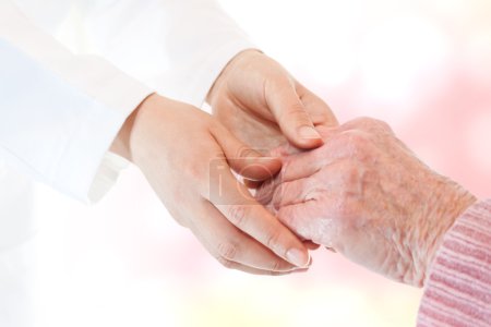 Doctor holding senior lady's hand