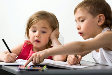 Careful brother shows to his smaller sister the color of felt-tip pen which is better for drawing