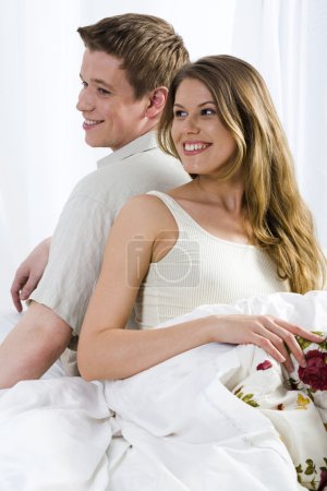 Young laughing couple lying in the bed
