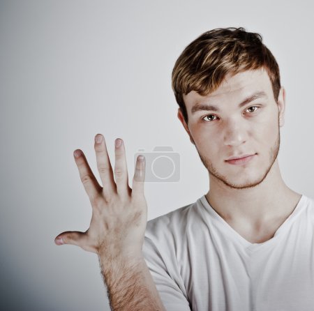Young man holding up five fingers