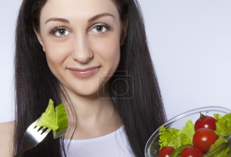 Closeup of a pretty young woman eating salad