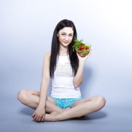 Portrait of a pretty young woman eating vegetable salad