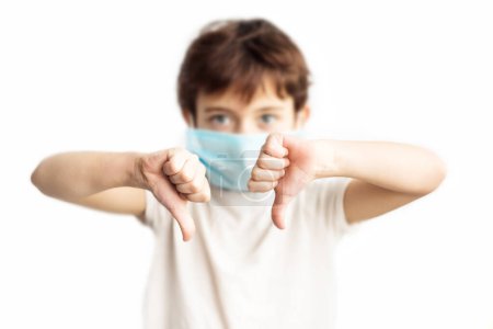Child in blue medical mask on face with fingers down. Coronavirus protection. Girl with face in mask. Children and illness. Medical care. Illness covid-2019 prevention.