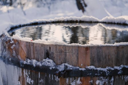 Big barrel with clean cold water outdoors in forest covered with snow. Winter swimming concept