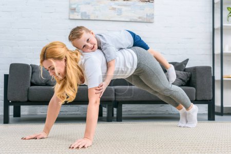 Mother doing plank with little son on back