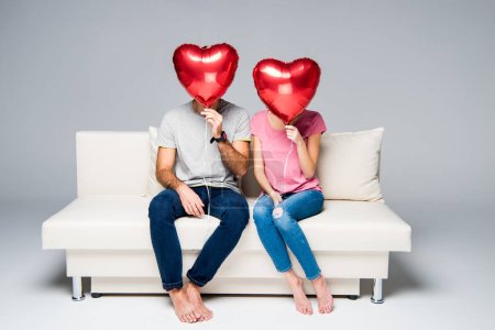 Couple sitting on couch with red balloons
