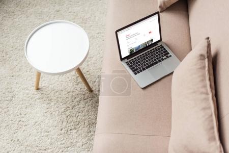 high angle view of laptop standing on cozy couch with airbnb website on screen