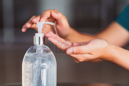 Closeup Asian woman hand using wash hand sanitizer gel pump dispenser before work over