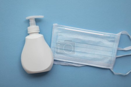 Protective medical mask and anti bacterial hand soap on a blue background