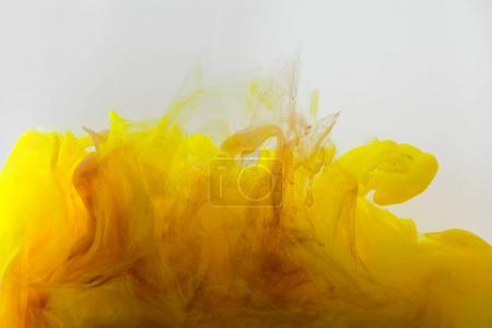 Close up view of mixing of yellow and brown inks splashes in water isolated on gray