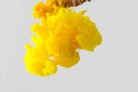 Close up view of bright yellow ink  splash in water isolated on gray