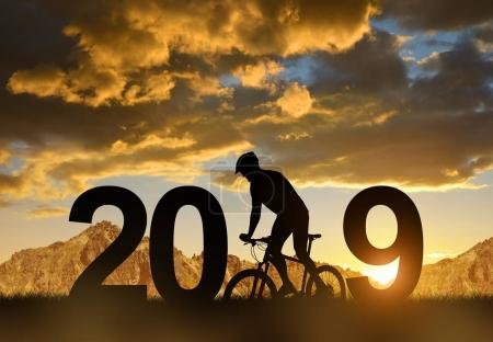 Silhouette of a cyclist on bike in the sunset. Concept of New Year 2019.