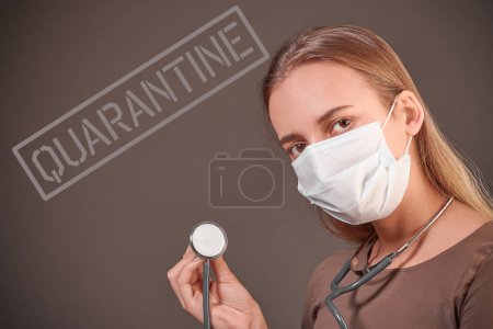 Close-up portrait of a girl in a medical mask on her face with a stethoscope. Students are quarantined.