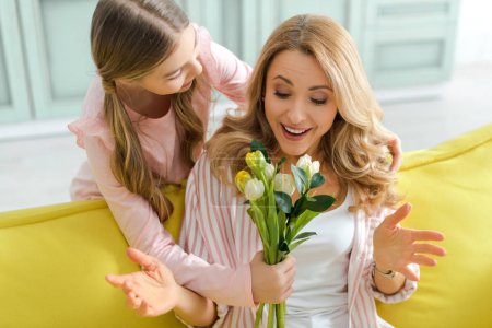 cute kid giving bouquet of tulips to surprised mother