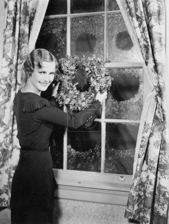 Woman hanging up a holiday wreath