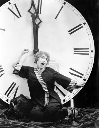 A young woman stretching in front of a giant clock striking midnight