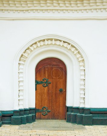 Ancient door in a white wall of a monastery