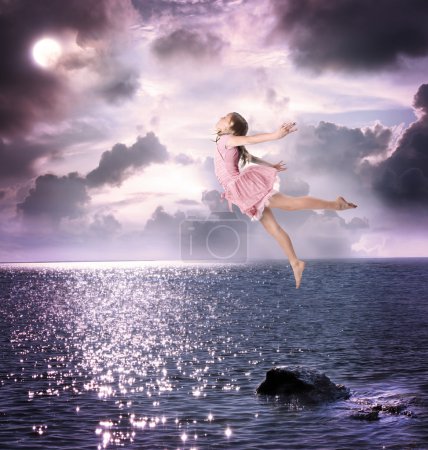 Little girl jumping into the night sky