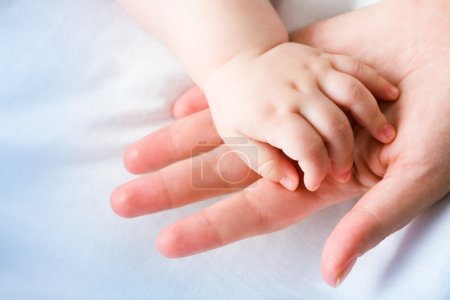 Moms palm with newborn baby hand on its surface