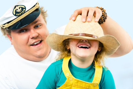 Man putting hat on his daughter's head while she laughing
