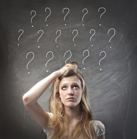 Young woman with doubtful expression and question marks over her head
