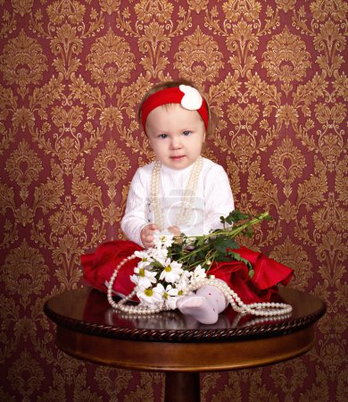 Little girl in beautiful dress sitting on the table