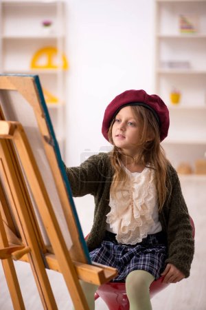 Young small girl enjoying painting at home